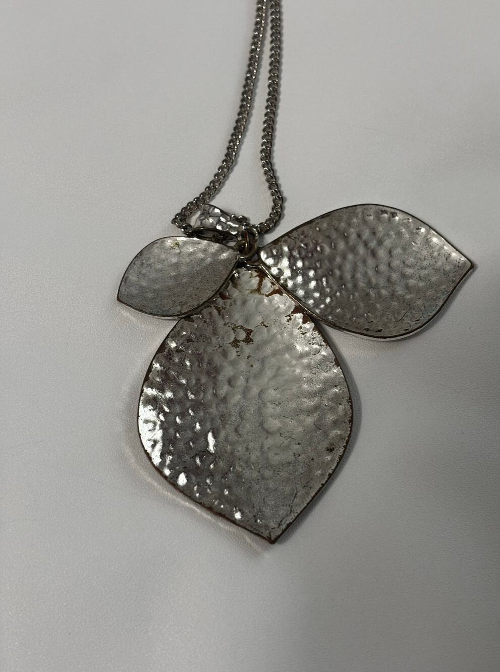 Silvertone hammered metal triple leaf-style pendant on 32 inch silver chain